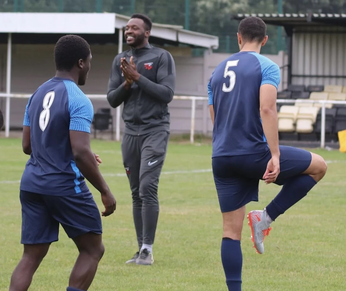 A coach speaking with players on the training ground